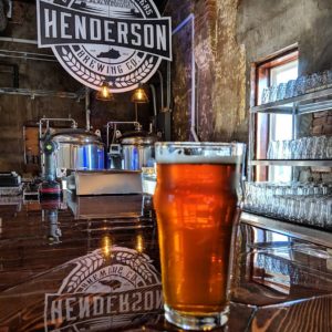 An amber pint of cold craft beer sits at the bar at Henderson Brewing Company