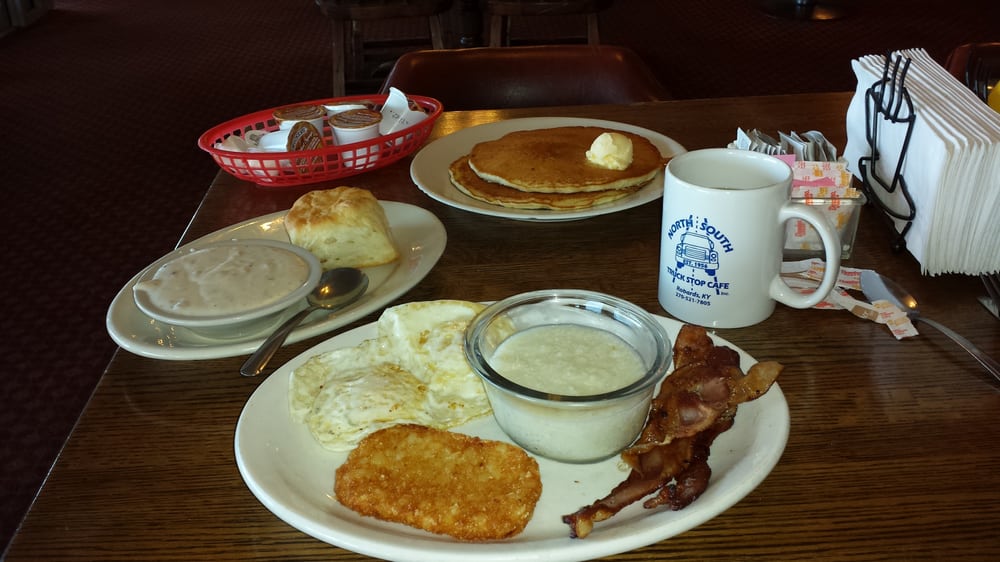 A hearty truck stop breakfast with a double stack of buttery pancakes, biscuits and gravy, eggs over easy, grits, bacon and a hash-brown accompanied by a cup of North South coffee 